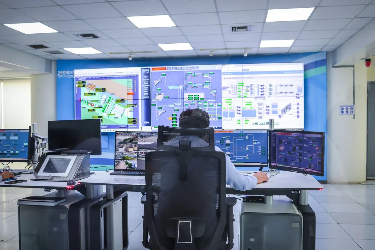 An operator at a wall of live system schematics in a control room