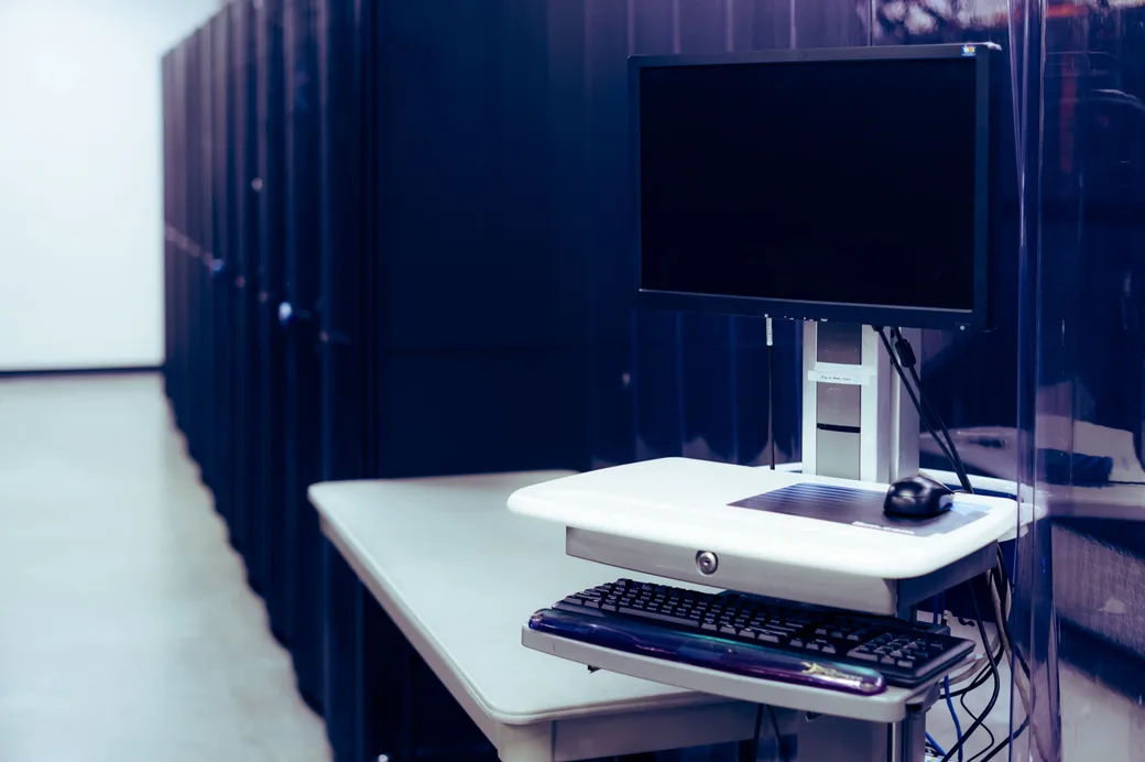 A workstation beside a row of server racks in a data hall